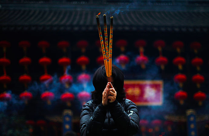 A woman holds incense sticks at the Old City God Temple in Yuyuan Garden in downtown Shanghai. ?Photo by Reuters