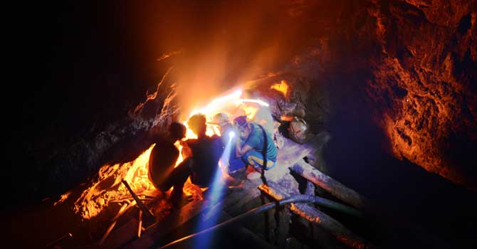 Indian coal miner, Surya Limu (inside hole), squats with other miners by a fire to keep warm hours before dawn, inside the face of a 50 meter deep shaft in Rymbai village in the northeastern state of Meghalaya. Unlike his more experienced colleagues, Limu moves slowly down the precarious mine steps, his delicate features straining with the effort. Child labour is officially illegal in India, with several state laws making the employment of anyone under 18 in a hazardous industry a non-bailable offence. -Photo by: AFP