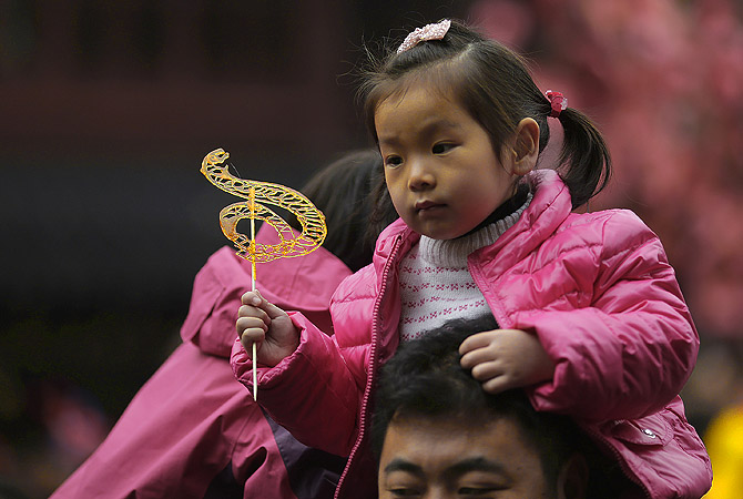 A child holds a snake-shaped candy on the shoulders of an adult at the Yuyuan Garden in Shanghai, China, on the second day of the Chinese Lunar New Year. Chinese celebrate the arrival of the Year of the Snake, according to the Chinese Zodiac.?Photo by AP