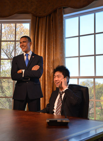 A Japanese man uses a phone next to the wax figure of US President Barack Obama. ?Photo by AFP