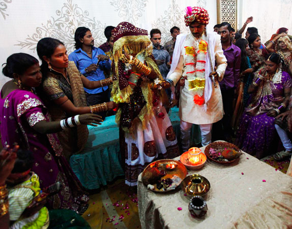 A bride and her groom, helped by relatives, perform a ritual during the ceremony.
