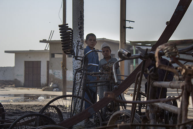 Children from around the area look at the ruins of an auto rickshaw workshop.