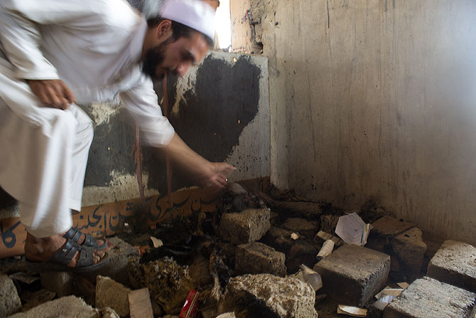 Mohammad Arif, a shopkeeper, points towards burned documents beneath the debris.