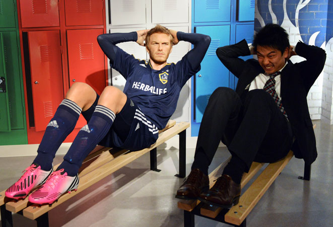 A man mimics the wax figure of football star David Beckham. ?Photo by AFP