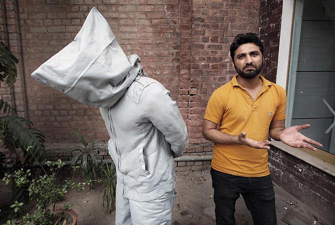 Saud Baloach, 28, a fine art artist, stands near his sculpture called "No Fear" during an interview with Reuters at Government College University.