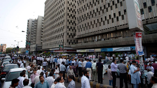 People evacuate buildings and gather on road after a tremor of an earthquake was felt in Karachi.