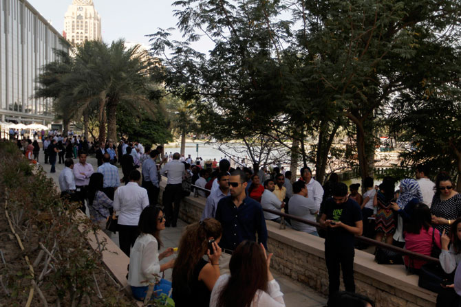 People wait outside after evacuating offices in Dubai Media City following earthquake tremors in Dubai.