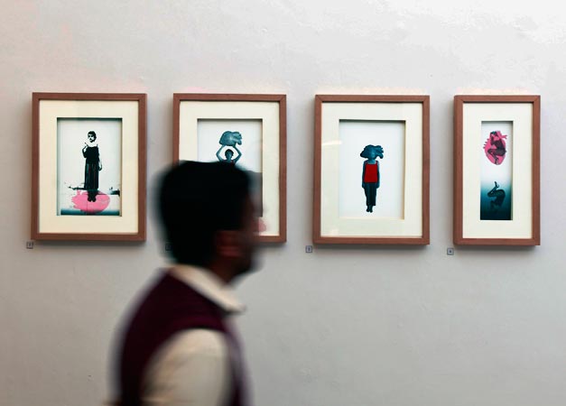 Man walking past a series of painting at Government College University in Lahore.