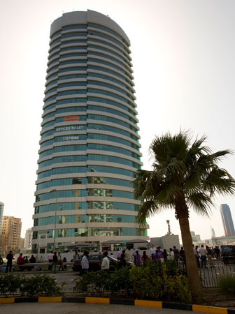 Office workers stand outside their office building following tremors in central Manama.