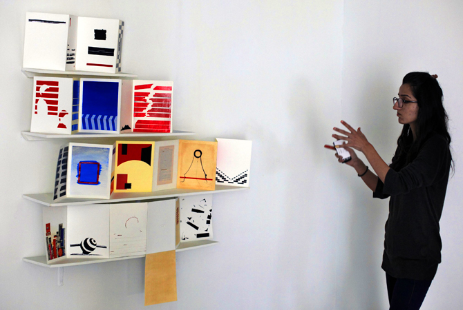 Schezre Syed, 23, a graduate student from the National College of Arts (NCA), gestures beside her work during an interview with Reuters at National Art Gallery.