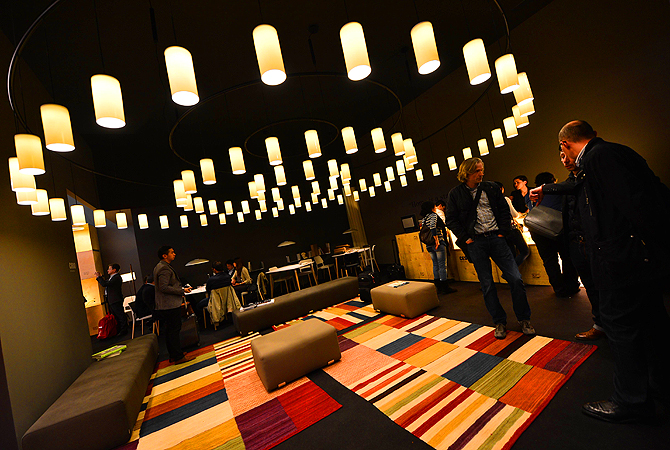Visitors walk in a stand of the Euroluce lightning trade fair as part of the Milan's annual furniture fair at the Fiera Milano in Rho.