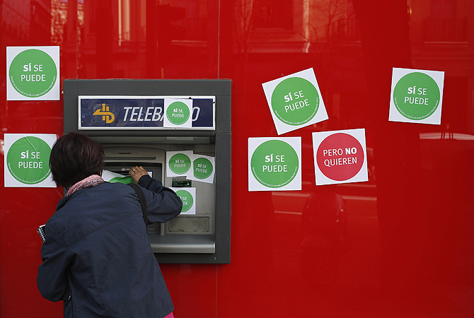 A woman uses an ATM machine at Santander bank branch during an "escrache" (denunciation) protest near the house of Spanish Parliament Chairman Jesus Posada in Madrid. Spanish protesters seeking to stop a wave of evictions have resorted to embarrassing politicians at their homes over harsh mortgage laws that have multiplied the pain of a property crash in the recession-hit country. Inspired by Latin American human rights campaigns from the 1990s, the "escraches" - Argentine slang for denunciation - have involved pro