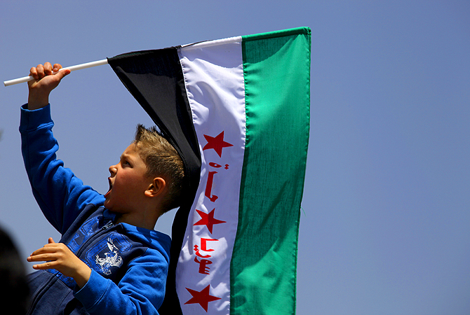 A boy waves the Syrian revolutionary flag as protester chant anti-Bashar Assad slogans and pro-Jabhat al-Nusra and Free Syrian Army slogans, in front of the Syrian embassy, in Amman, Jordan. The Arabic writing on flag reads "free Syria." With a fresh influx of weapons, Syrian opposition fighters have made significant gains in the past weeks, particularly in the southern province of Daraa, where rebels have been advancing in the region between the Jordanian border and the capital, Damascus.