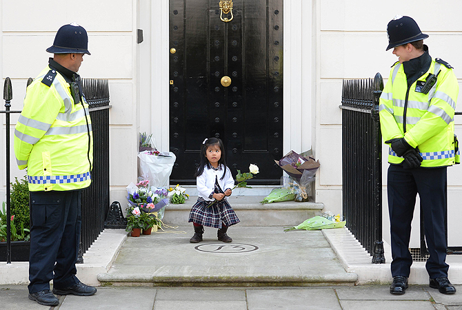 British police look on as a girl holds a rose amid floral tributes at the home of former British Prime Minister Margaret Thatcher in central London. British lawmakers will interrupt their holidays for a special session of parliament on April 10 to debate the legacy of Margaret Thatcher, who died on April 8 aged 87 after suffering a stroke.