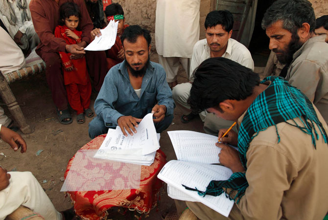 Supporters of Pakistan's political party Tehreek-e-Insaf (PTI), led by Pakistani cricketer-turned-politician Imran Khan, look for their names on the voters' list, which they say is provided by the Pakistani election commission, as they sit beside the PTI's election campaign office on the outskirts of Islamabad, May 6, 2013.