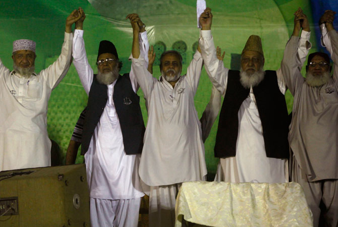 Syed Munawar Hassan (2nd L), leader of political and religious party Jamaat-e-Islami, joins hands with the party's local leaders during an election campaign rally in Karachi, May 5, 2013.