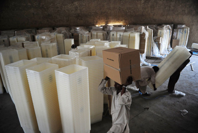 Pakistani workers carry ballot boxes and electoral materials to be transported to polling stations for the forthcoming parliamentary elections, in Karachi on May 6, 2013.