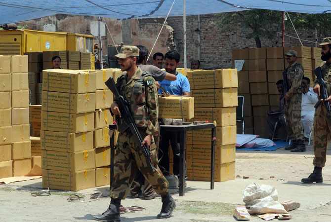 Pakistani army soldiers stand guard beside boxes of electoral materials at the state-run Printing Corporation of Pakistan, before being transported to polling stations for the forthcoming parliamentary elections, in Lahore on May 6, 2013.