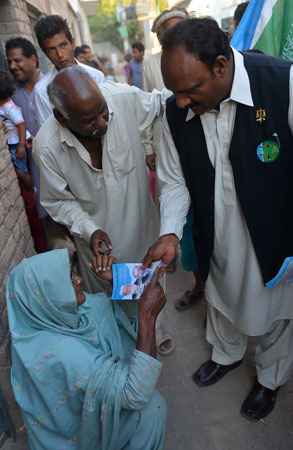 Pervaiz Masih (R) gives an election pamphlet to a Christian woman during his election campaign.