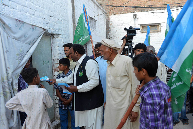 Pervaiz Masih (C) hands out leaflets.