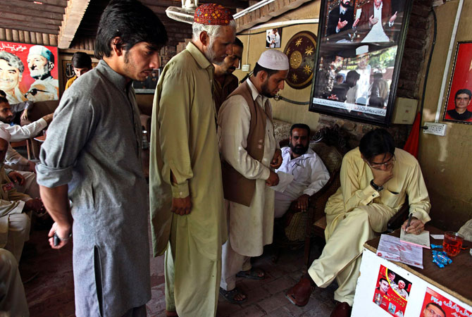 Haroon Bilour (R) meets with constituents seeking help for problems at his house.
