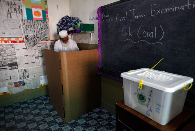 A voter stamps his ballot papers inside a booth at a polling station during re-polling.