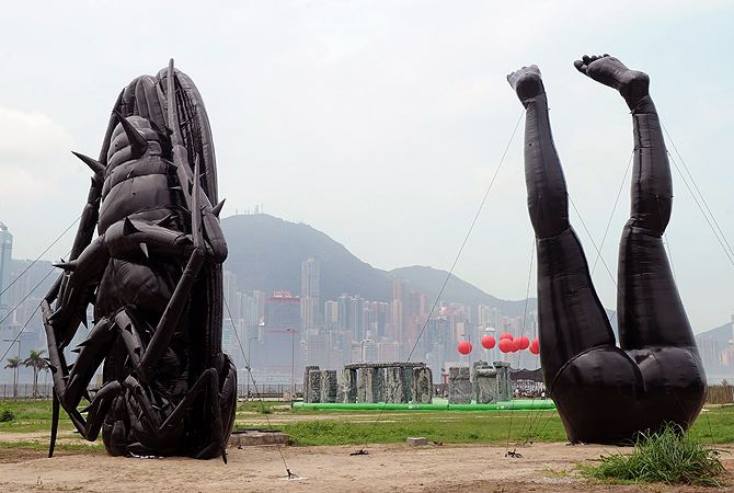 A journalist takes photos of sculptures by Hong Kong artist Tam Wai Ping titled "Falling into Mundane World" during a press preview of the Mobile M+: Inflation! exhibition in Hong Kong on April 24, 2013. Mobile M+: Inflation! presented six giant inflatable sculptures installed next to M+, Hong Kong’s future museum for visual culture, and will open to the public from 25 April – 9 June. — AFP Photo