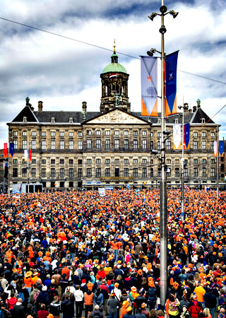 People, most of them wearing orange tee shirts, hats or plastic crowns, gather on April 30, 2013 at the Dam Square in Amsterdam, The Netherlands, to attend the investiture of the country's new King. — AFP Photo