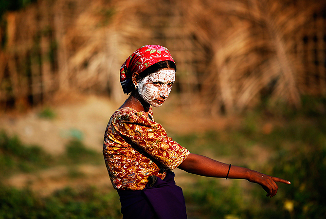 A Rohingya Muslim woman wearing traditional thanaka paste on her face gestures in a camp for people displaced by violence. — Reuters Photo