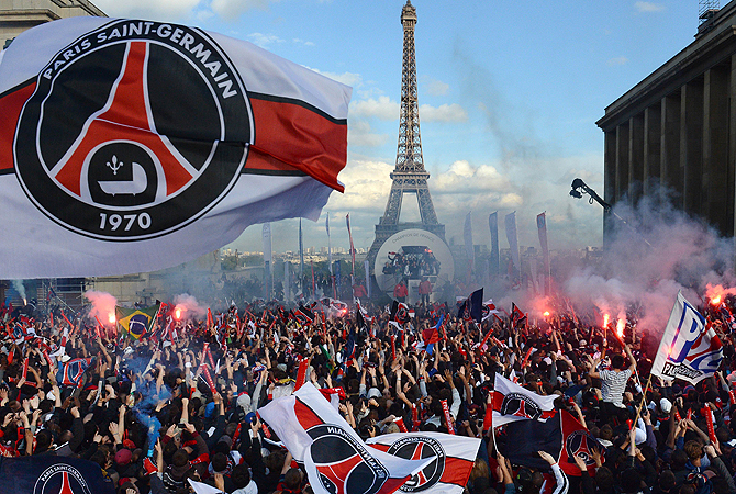 Paris Saint-Germain's supporters cheer as their team parades on a bus, on May 13, 2013 in Paris, one day after Paris secured French L1 football championship title. — AFP Photo
