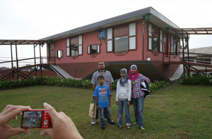 Tourists pose with an upside-down house in Tamparuli in Malaysia's state of Sabah on Borneo island September 17, 2012. Built for tourist attraction, the traditional Sabah village house was built with everyday households items like computer, refrigerator, sofa sets, dining table and beds - but all items are upside down.