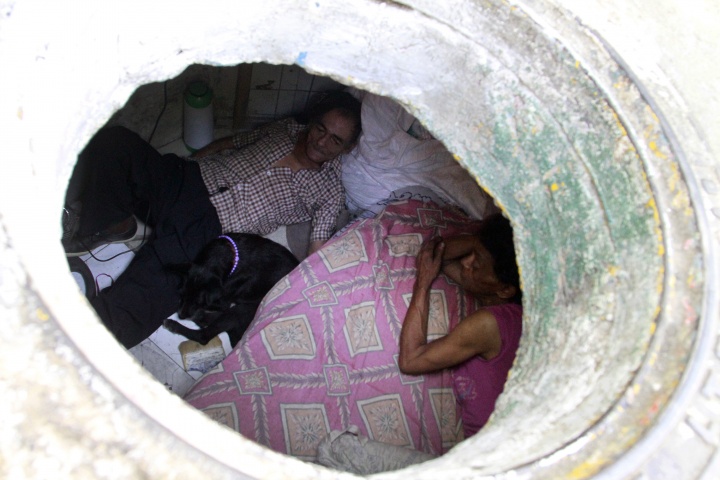 Miguel Restrepo (L), 62, and wife Maria Garcia are seen from their sewer home in Medellin December 4, 2012. The former drug addict has been living in an abandoned sewer with his wife and dog Blackie for 22 years. Their home, which is fitted with a kitchen, a fan, tv, a chair and a bed, is a 6 square meter wide and 1.4 meters high tunnel that leaks when it rains, and requires a manhole cover.