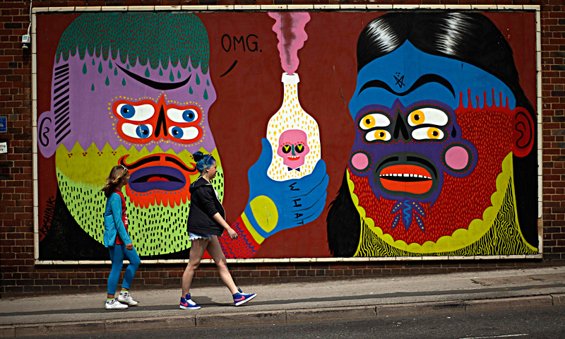 Two girls walk past a mural painted on a wall in Blackpool, northern England June 18, 2013. The mural is part of the "Sand, Sea and Spray" outdoor art festival, which has seen 40 urban artists from around the world paint murals on buildings across the town centre. — Reuters Photo