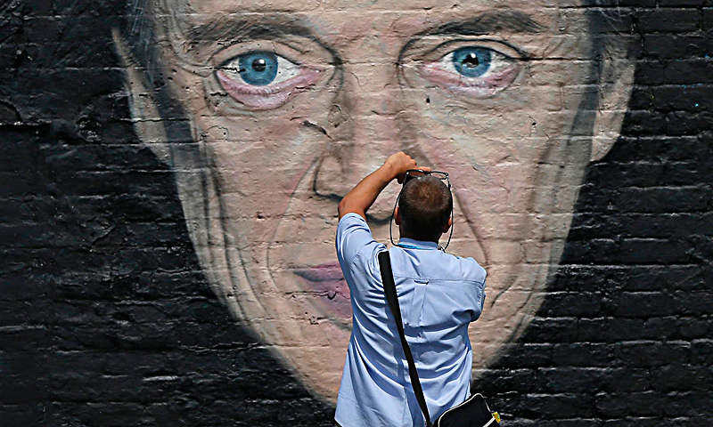 A woman walks down an alley way between two painted murals in Blackpool, northern England June 18, 2013. The mural is part of the "Sand, Sea and Spray" outdoor art festival, which has seen 40 urban artists from around the world paint murals on buildings across the town centre. — Reuters Photo