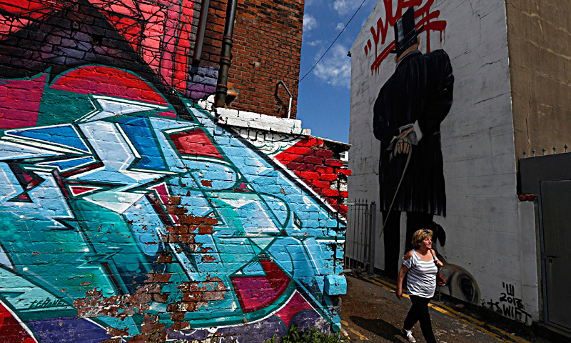 A man pushes his bicycle past murals painted on the side of a building in Blackpool, northern England June 18, 2013. The mural is part of the "Sand, Sea and Spray" outdoor art festival, which has seen 40 urban artists from around the world paint murals on buildings across the town centre. — Reuters Photo