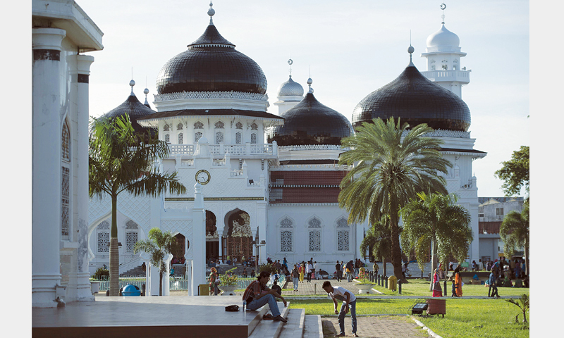 A MEMORIAL (left) to the Dec 26 tsunami victims in Meulaboh. Acehnese enjoying their weekend around the Baitur Rahman Mosque in Banda Aceh.—AFP