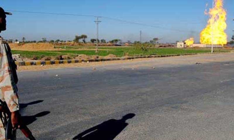 A Pakistani paramilitary soldier looks at the fire flaring up from a pipeline.&mdash;AFP/File