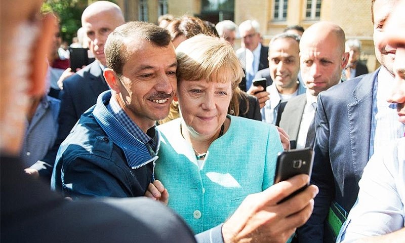 A migrant takes a selfie with German Chancellor Angela Merkel during a visit to a reception centre in Berlin. ─AFP/File