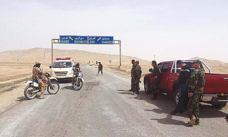 Forces loyal to Syria&rsquo;s President Bashar al-Assad stand near a road sign that shows the direction to the historic city of Palmyra in this picture provided by the Syrian news agency SANA on Thursday.&mdash;Reuters