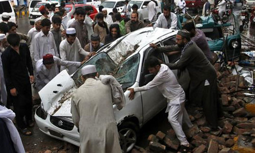 پشاورمیں دیوار گرنے سے تباہ ہونے والی گاڑیوں کو ہٹانے کی کوشش کررہے ہیں—فوٹو/اے پی