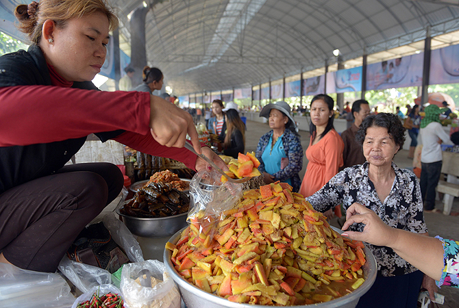 A Cambodian vendor (L) packages food for a customer at a tourist site on the outskirts of Phnom Penh. Cambodia's economic growth accelerated to 7.3 percent in 2012 thanks to buoyant activity in the agricultural, tourism, construction and garment sectors, Prime Minister Hun Sen said.—Photo by AFP