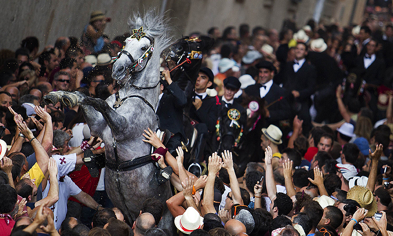 A horse rears in a crowd during a horse parade of the traditional San Juan (Saint John) festival in the town of Ciutadella, on the Balearic Island of Menorca, on the eve of Saint John's day.—Photo by AFP