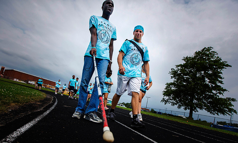 Ahmat Djouma walks with his white cane with counselor Adam Dwyer at Camp Abilities in Brockport, New York.