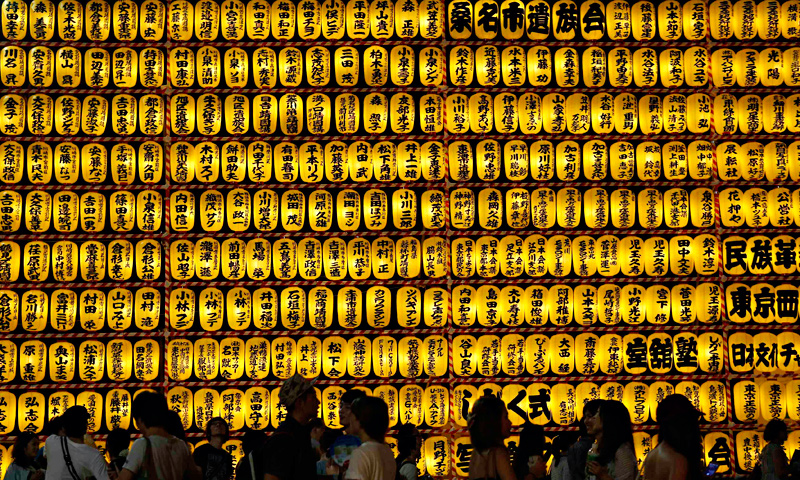 People walk in front of paper lanterns during the Mitama Festival at the Yasukuni Shrine in Tokyo, July 13, 2013.