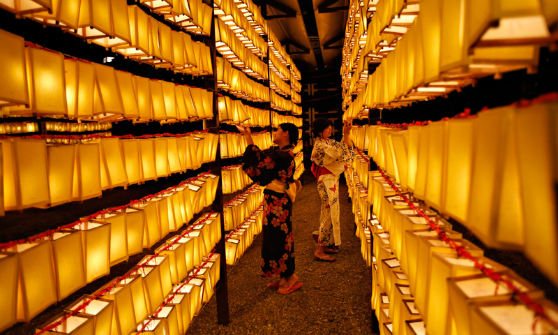 Women in yukatas, or casual summer kimonos, look at paper lanterns during the Mitama Festival at the Yasukuni Shrine in Tokyo.