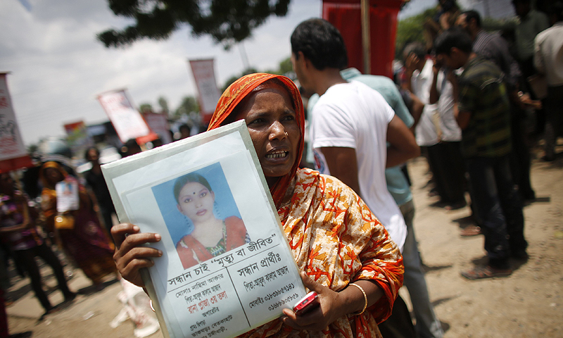 A woman holds a photograph of her relative, a garment worker who is still missing after the collapse of the Rana Plaza building, as she and others take part in a protest in front of the head office of Bangladesh Garment Manufactures & Exporters Association (BGMEA) in Dhaka July 21, 2013. Activists of Garments Sramik Sangram Parisad, a workers' rights movement, staged a protest demanding the fast payment of compensation for the Rana Plaza victims and to increase the minimum wage of all garments workers, local media