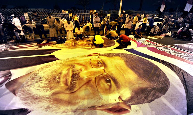 Members of Muslim brotherhood perform prayers on a poster of ousted Egyptian president Mohamed Morsi. — AFP Photo