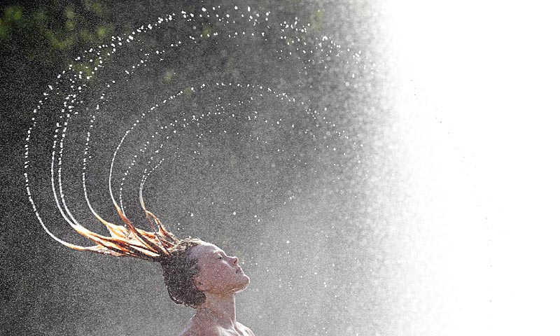 A woman cools off in the water of a fountain in Berlin as temperatures in Germany topped the 30 degree Celsius mark. — AFP Photo