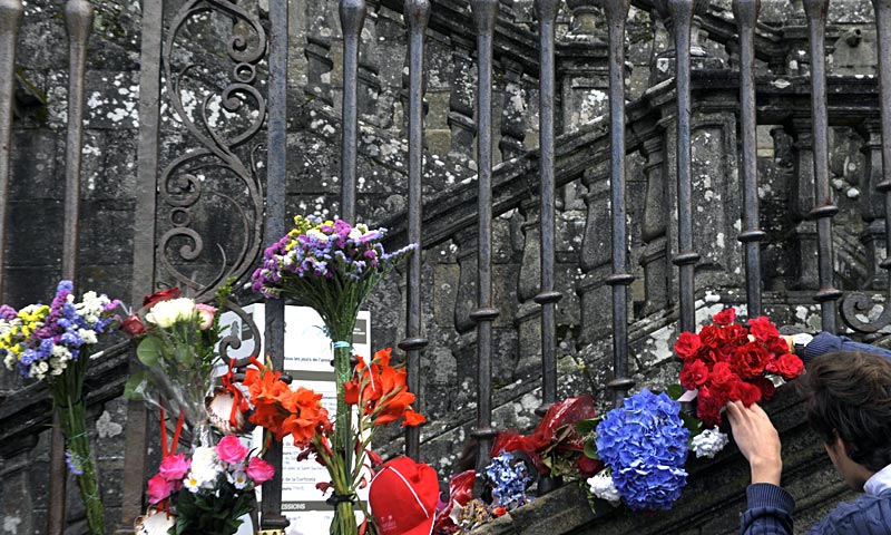 A man displays flowers at the fence of Santiago de Compostela cathedral to honour the victims of a train accident, at Obradoiro square, in the northern Spanish city of Santiago de Compostela. — AFP Photo