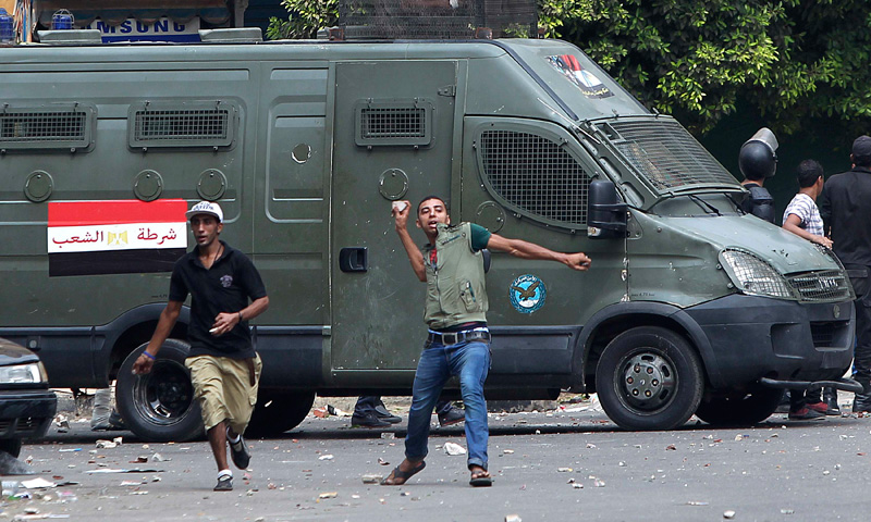 A local resident throws stones towards pro-Morsi protestors.